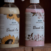 Stübben Care Brush On Sunflower und Cherry Blossom im Lifestyle-Foto vor dunklem Holzhintergrund. Mähnenspray für Pferde mit Sonnenblumen- und Kirschblüten-Design.