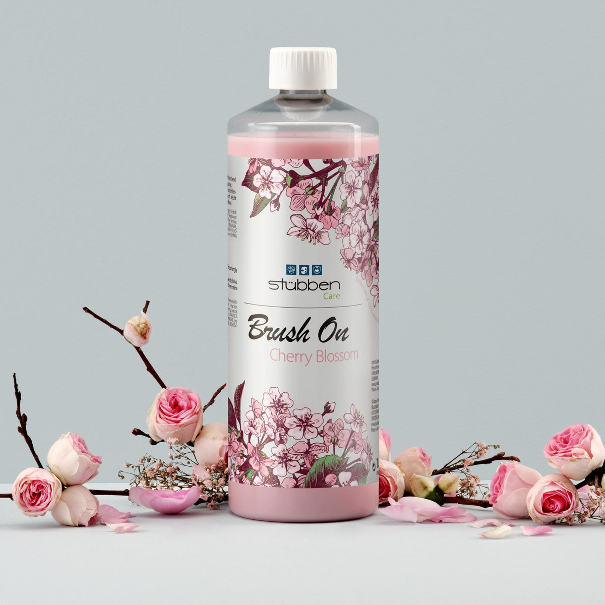 Stübben Brush On Cherry Blossom 1 Liter Nachfüllflasche im Stillleben mit Kirschblütenzweigen und Rosenblüten. Praktische Vorratsflasche für das Mähnen- und Schweifspray in der täglichen Pferdepflege.