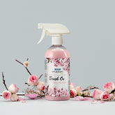 Stübben Brush On Cherry Blossom 500 ml Sprühflasche im Stillleben mit Kirschblütenzweigen und Rosenblüten. Mähnenspray und Schweifspray mit Kirschblüten-Design für Glanz, Volumen und leichte Kämmbarkeit.