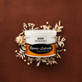 Vor einem groben braunen Lederhintergrund mit hellen Trockenblumen-Akzenten präsentiert sich die ergiebige 500 g Vorratsdose der Stübben Glycerin Sattelseife, die für geschmeidiges Leder und langanhaltende Elastizität durch rückfettende Reinigung steht.