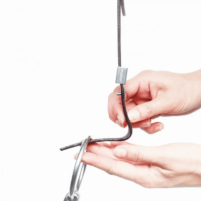 Detailaufnahme der Funktionsweise des Stübben Slide&amp;Lock-Systems an der Stübben-Trense: Eine Hand schiebt die silberne Metallabdeckung, den Slider nach oben, um den Dorn am Backenstück freizugeben und den Gebissring für einen schnellen, werkzeuglosen Gebisswechsel mit nur einem Handgriff auszutauschen.