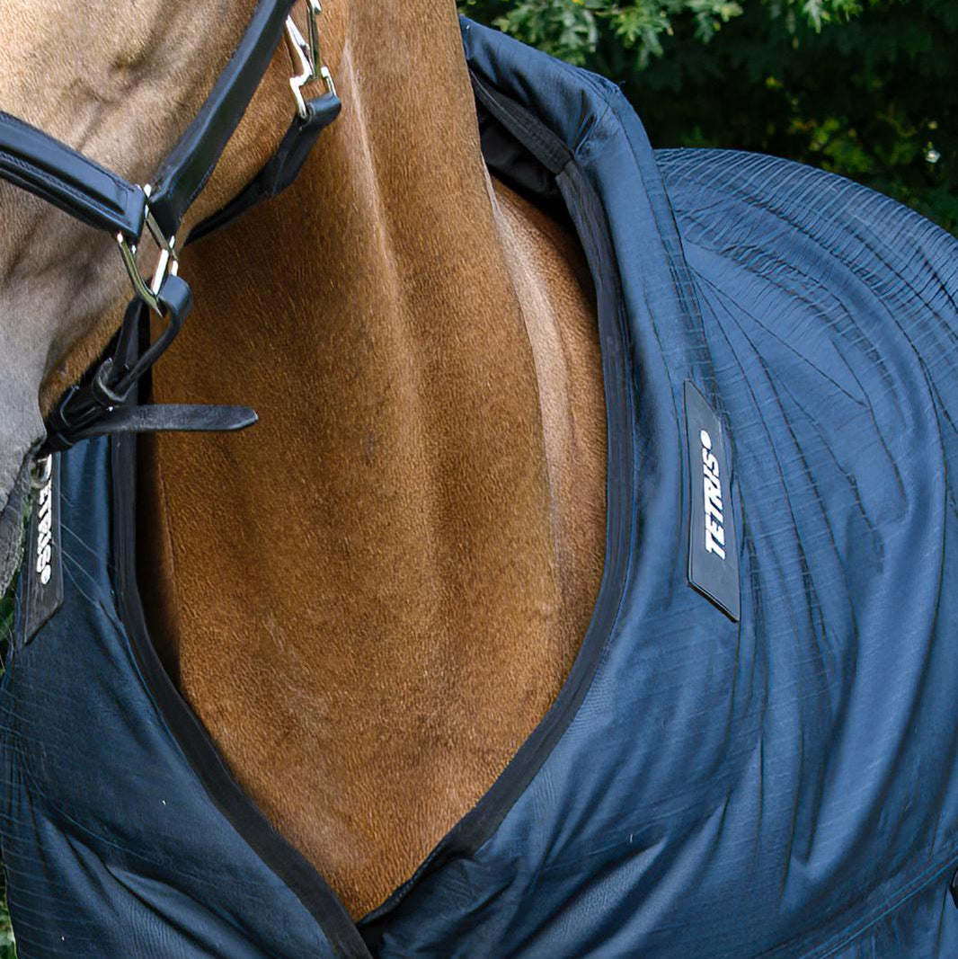 ie Frontalansicht der Trust Tetris Outdoordecke verdeutlicht die perfekte Passform am geschlossenen Halsbereich, wobei das Volumen der innenliegenden Polsterblöcke des Tetris-Systems deutlich erkennbar ist, um eine konsequente Last- und Druckverteilung des Decken-Eigengewichts zu garantieren und Haarbruch sowie Scheuerstellen selbst in intensiven Bewegungsabläufen pferdefreundlich zu verhindern.