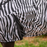 Detailaufnahme der Waldhausen Ekzemerdecke Zebra Premium in schwarz-weiß, die die dunkel abgesetzte Gehfalte und das sichtbare Waldhausen-Logo zeigt. Dieses Zebra-Design bietet Pferden und Ponys maximale Bewegungsfreiheit auf der Weide beim Galoppieren, Spielen und Buckeln. Der funktionale Zebra-Print dient als mechanischer Fliegenschutz zur Abwehr von Kriebelmücken, während die elastische Gehfalte dieser Sommerdecke eine optimale, körpernahe Passform beim Freilauf.