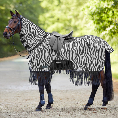 Die Waldhausen Fliegen-Ausreitdecke Zebra mit Fransen in schwarz-weiß gestreift auf einem gesattelten und getrensten Pferd vor einem Weg und Wald für den Ausritt im Sommer. Das luftdurchlässige Gewebe umhüllt Hals, Rücken und Flanken als mechanischer Fliegenschutz. Der auffällige Zebra-Print wehrt Bremsen, Fliegen und Kriebelmücken optisch ab, während die sich ständig bewegenden Fransen am unteren Saum den Bauch- und Beinbereich vor störenden Insekten schützen.