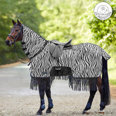 Waldhausen Fliegen-Ausreitdecke Zebra mit Fransen und eingeblendetem UV-Protection-Button am gesattelten Pferd im Gelände. Gut erkennbar ist der Materialrückschnitt im Bereich der Sattel- und Schenkellage für engen Kontakt vom Reiterbein und eine gefühlvolle Hilfengebung. Das feste Halsteil deckt den Mähnenkamm ab, während der Schweiflatz Schweifrübe und Schweifansatz schützt. Diese Reitdecke vereint optische und mechanische Fliegenabwehr für entspannte Sommer-Ritte mit dem Pferd.