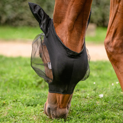 Grasendes Pferd mit gesenktem Kopf und der schwarzen Waldhausen Fliegenmaske Skinny. Sichtbar ist der Bereich von Ganaschen und Kehle, der komplett ohne Klettverschluss oder Reißverschluss auskommt. Das elastische Material sorgt für eine stabile Passform am Pferdekopf. Verfügbar in den Größen Shetty, Pony, Vollblut, Warmblut und Warmblut Extra (Kaltblut) bei ePony Reitsport.