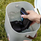 Blick von oben in den Waldhausen Multibag ECO, in dem eine schwarze Waldhausen Health + Care Ice-Layer Kühlgamasche vollständig im klaren Wasser untergetaucht ist. Das Bild verdeutlicht, wie sich das saugfähige Material komplett vollsaugt, um den langanhaltenden Cooling-Effekt am Pferdebein zu aktivieren. Diese unkomplizierte Methode nutzt die Verdunstungskühlung im Sommer und funktioniert ohne Gefrierfach – ideal für die Pferdepflege und Pferdewellness.