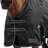 Detailaufnahme des doppelten Brustverschlusses der Waldhausen Outdoordecke Arctic 50 g in Schwarz. Die robusten T-Verschlüsse sind mit Klettabdeckungen geschützt, und können ein Hängenbleiben im Offenstall oder Paddock reduzieren. Der doppelte Brustverschluss ermöglicht einfaches Ein- und Ausdecken von Pferd oder Pony. Reflektierende Kontrastnähte in Weiß auf den Klettlaschen und dem Einfassband erhöhen die Sichtbarkeit bei Dunkelheit.