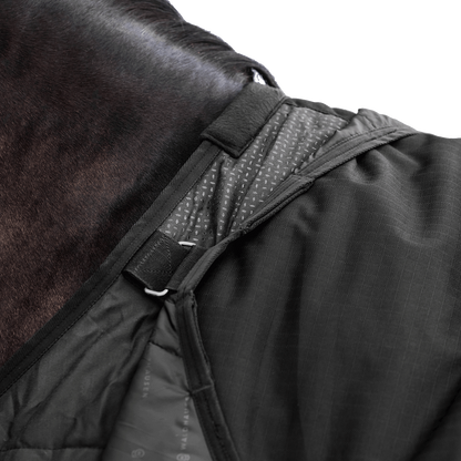 Detailaufnahme des Waldhausen-Clip-In-Deckensystems der Outdoordecke Arctic 100 g in Schwarz im Schulterbereich von Pferd oder Pony. Integrierte Ösen und Ringe ermöglichen das flexible Befestigen separater Unterdecken, um die Wärmeleistung individuell an wechselnde Temperaturen im Herbst und Winter anzupassen. Die funktionale 600D-Ripstop-Pferdedecke bietet als modulare äußere Deckenkomponente maximale Flexibilität im Stallalltag.