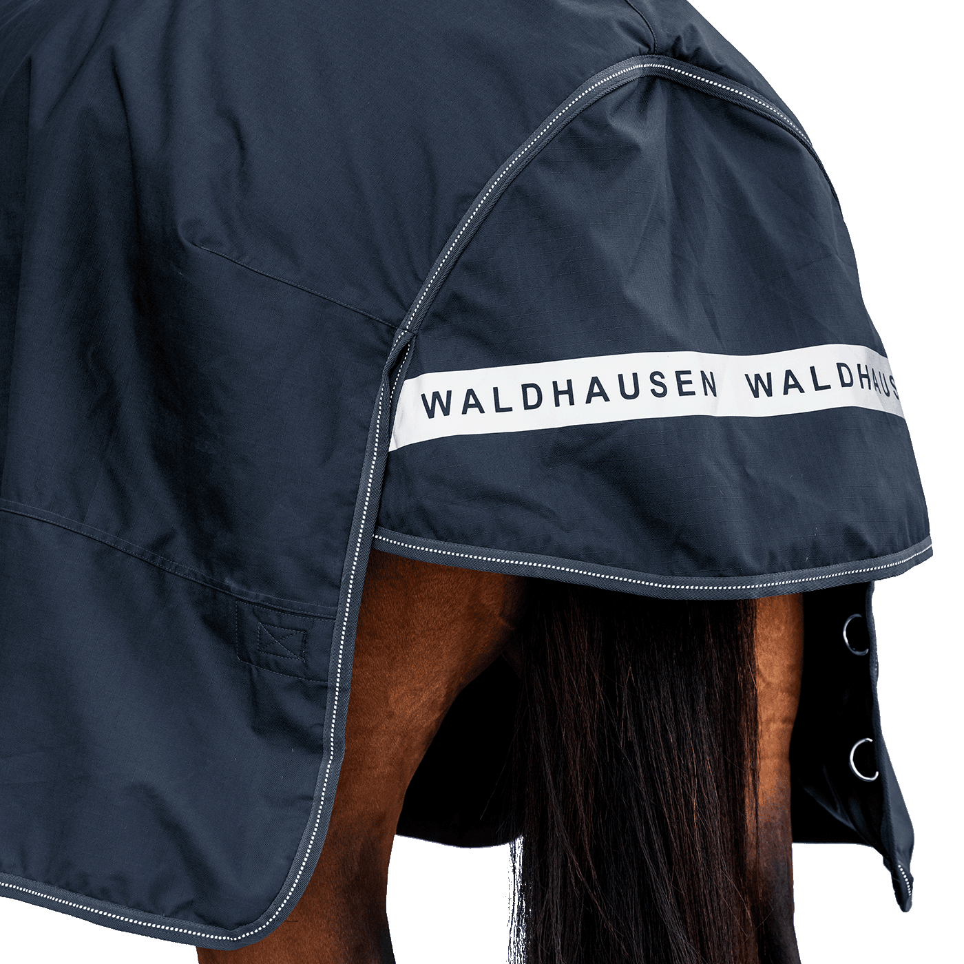 Rückansicht der dunkelblauen Waldhausen-Outdoordecke Arctic 200 g in Nachtblau mit Fokus auf den langen Schweiflatz. Der großzügige Schweiflatz schützt Schweif und Schweifrübe des Pferdes zuverlässig vor Wind, Regen und Kälte. Die breite, reflektierende Waldhausen-Applikation sorgt für optimale Sichtbarkeit von hinten im Dunkeln, auf der Weide, auf Wegen oder im Straßenverkehr. Die perfekte 600D-Ripstop-Regendecke für bessere Sichtbarkeit im Dunklen. D-Ringe für Beinschnüre sind zu sehen.