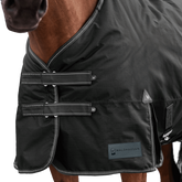 Detailaufnahme des doppelten Brustverschlusses der Waldhausen Outdoordecke Arctic 50 g in Schwarz. Die robusten T-Verschlüsse sind mit Klettabdeckungen geschützt, und können ein Hängenbleiben im Offenstall oder Paddock reduzieren. Der doppelte Brustverschluss ermöglicht einfaches Ein- und Ausdecken von Pferd oder Pony. Reflektierende Kontrastnähte in Weiß auf den Klettlaschen und dem Einfassband erhöhen die Sichtbarkeit bei Dunkelheit.