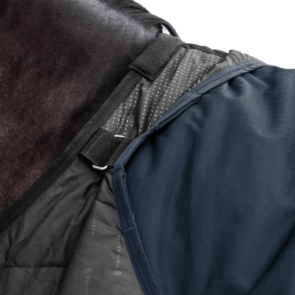Detailaufnahme des Waldhausen-Clip-In-Deckensystems der Outdoordecke Arctic Light ohne Füllung in Nachtblau im Schulterbereich von Pferd oder Pony. Integrierte Ösen und Ringe ermöglichen das flexible Befestigen separater Unterdecken, um die Wärmeleistung individuell an wechselnde Temperaturen im Herbst und Winter anzupassen. Die funktionale 600D-Ripstop-Pferdedecke bietet als modulare äußere Deckenkomponente maximale Flexibilität im Stallalltag.