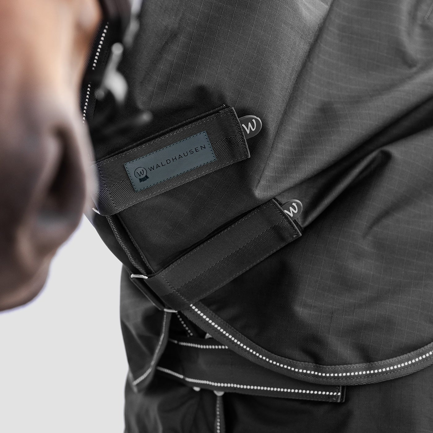 Detailaufnahme des Waldhausen Outdoorhalsteils  600 D Light in Schwarz am Pferdehals. Der Fokus liegt auf den zwei verstellbaren Klettverschlüssen zum einfachen Öffnen, Schließen und präzisen Anpassen der Passform für Pony und Pferd.