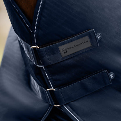 Detailaufnahme des braunen Waldhausen Outdoorhalsteils in Blau am Pferdehals. Der Fokus liegt auf den zwei verstellbaren Klettverschlüssen zum einfachen Öffnen, Schließen und präzisen Anpassen der Passform für Pony und Pferd.