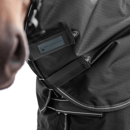 Detailaufnahme des Waldhausen Outdoorhalsteils in Schwarz am Pferdehals. Der Fokus liegt auf den zwei verstellbaren Klettverschlüssen zum einfachen Öffnen, Schließen und präzisen Anpassen der Passform für Pony und Pferd.
