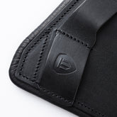 Nahaufnahme der Leder-Gurtschlaufe mit geprägtem Winderen-Logo am schwarzen Dressursattelgurt Pressure-Relief. Zu sehen sind die präzisen doppelten schwarzen Nähte und die hochwertige Verarbeitung des Vollnarbenleders. Diese funktionale Schlaufe fixiert die Sattelgurtstrippen beim Dressurkurzgurt sicher am Pferd und steht für erstklassige Handwerkskunst, Sicherheit und Langlebigkeit im Dressursport