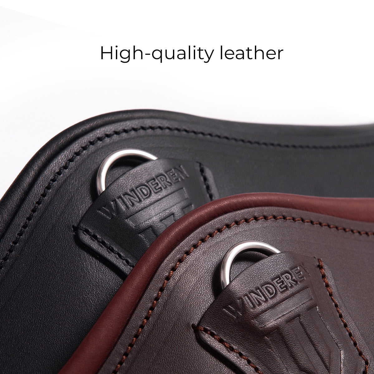 Detailansicht der Winderen Pressure-Relief-Dressursattelgurte in den Farben Schwarz und Braun aus hochwertigem Vollnarbenleder (high-quality leather). Zu sehen ist die präzise verarbeitete Lederabdeckung mit geprägtem Winderen-Logo und dem integrierten Karabiner zum schnellen Einhaken von Hilfszügeln. Dieser anatomische Lederkurzgurt bietet maximale Druckentlastung für empfindliche Pferde und Ponys bei Gurtzwang.