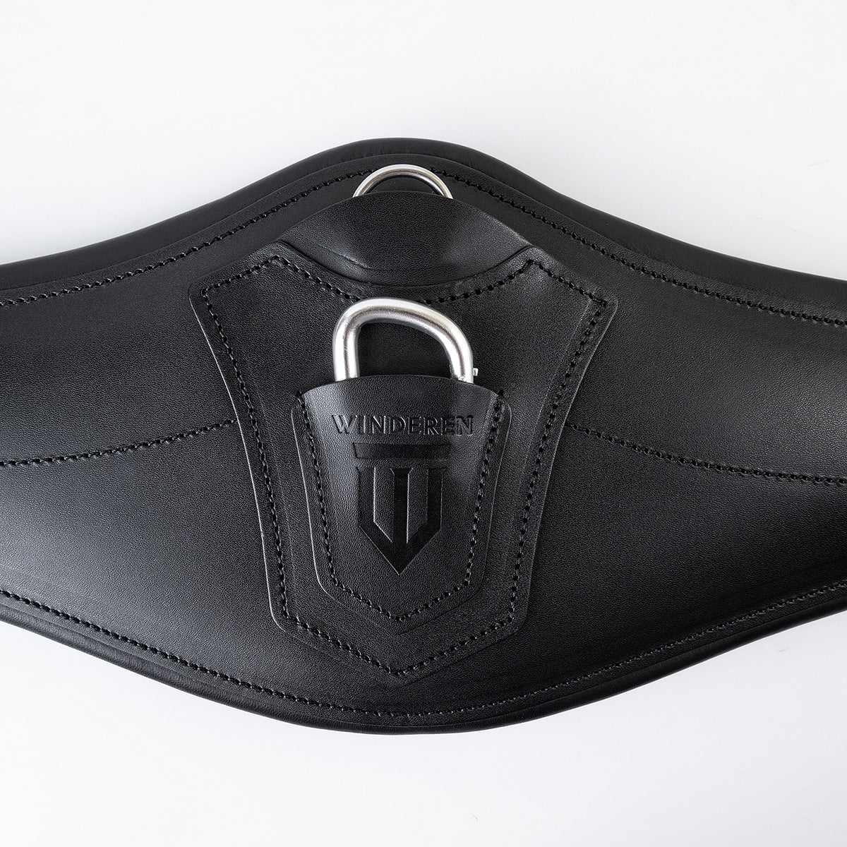 Detailansicht des schwarzen Winderen Pressure-Relief Springgurtes mit kleinem Bauchlatz aus hochwertigem Vollnarbenleder. Die Nahaufnahme zeigt die Leder-Schutzabdeckung mit geprägtem Winderen-Logo über dem halb versenkten Aluminium-Karabiner für das Einhaken von Vorderzeugen sowie den darüber liegenden Edelstahl-D-Ring für Hilfszügel wie Martingale.