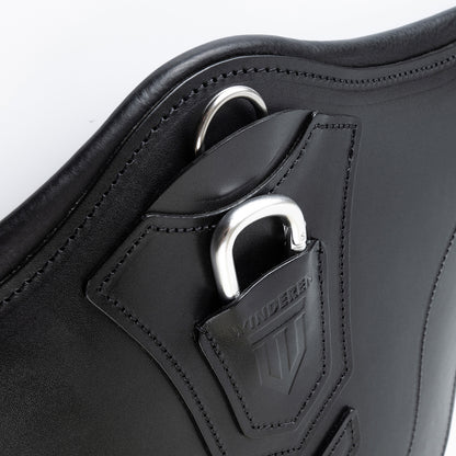Perspektivische Detailaufnahme der zentralen Bauchplatte des schwarzen Winderen Pressure-Relief Stollengurts aus Vollnarbenleder. Die Ansicht zeigt den halb versenkten Aluminium-Karabiner unter der geprägten Lederabdeckung für das schnelle Einhaken von Vorderzeugen ohne Verfangen sowie den flach integrierten D-Ring für Hilfszügel wie ein Martingal.